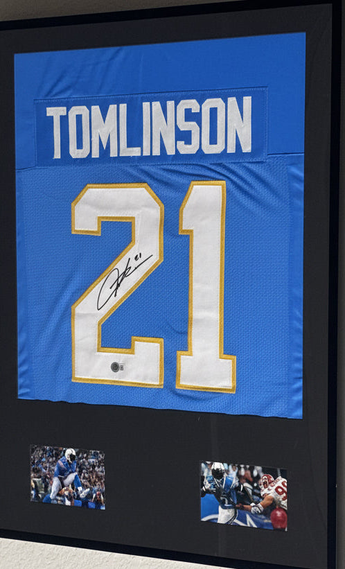 Framed sports jersey with number 21 and name 'Tomlinson' on a wall.